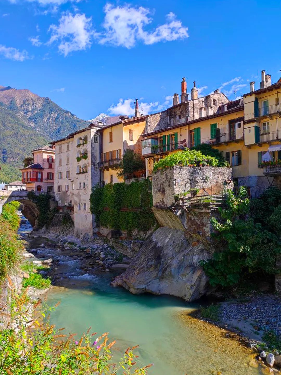 Historic stone houses above a turquoise river in Valchiavenna