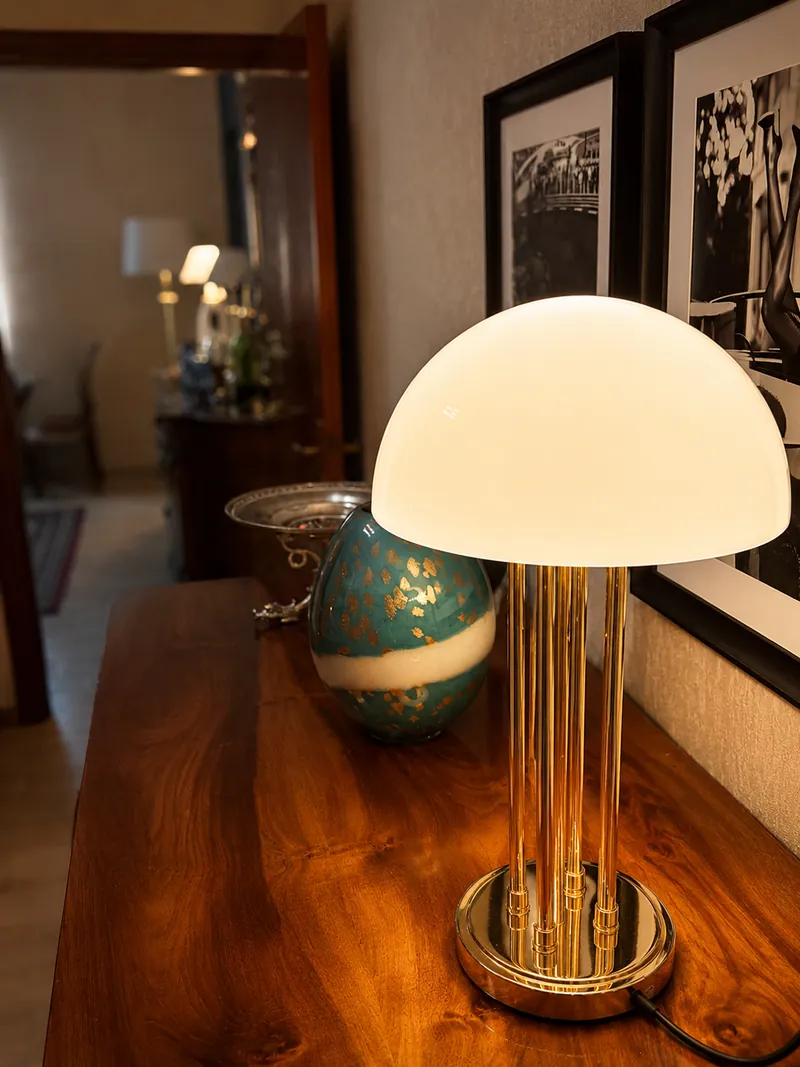 Brass and opal glass table lamp beside framed photographs