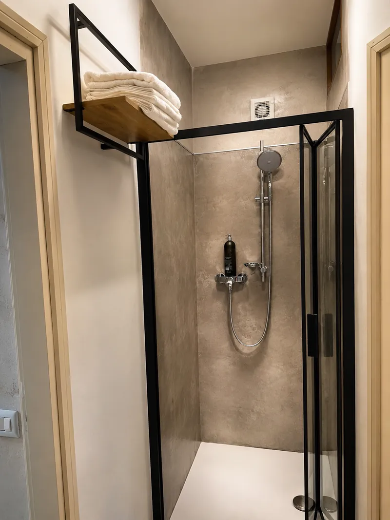 Walk-in shower with stone-effect tiling and folded white towels